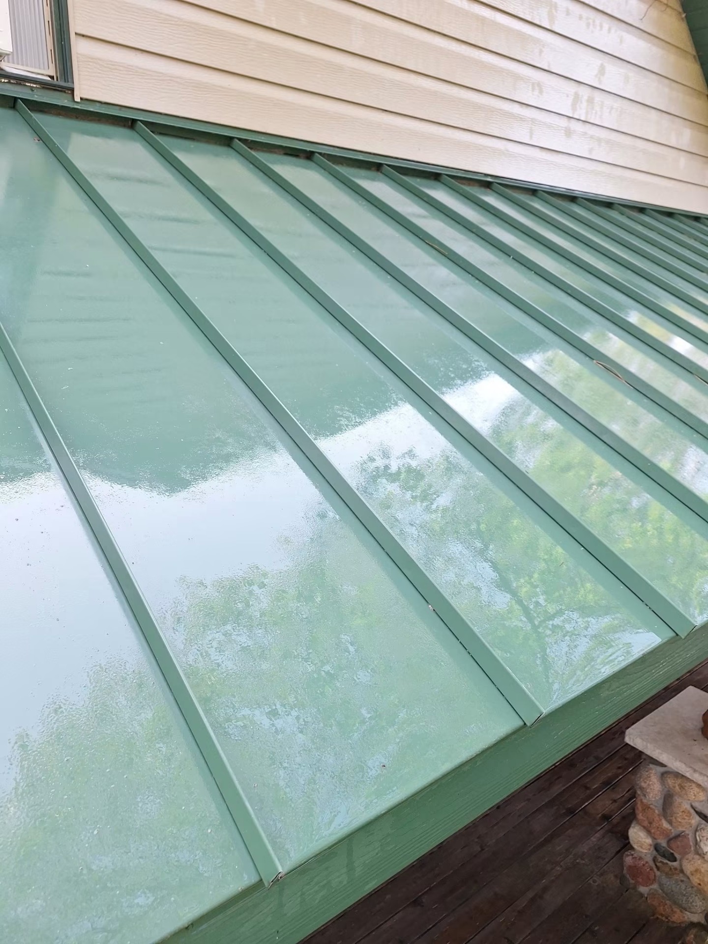 Same green metal roof shining clean after soft wash