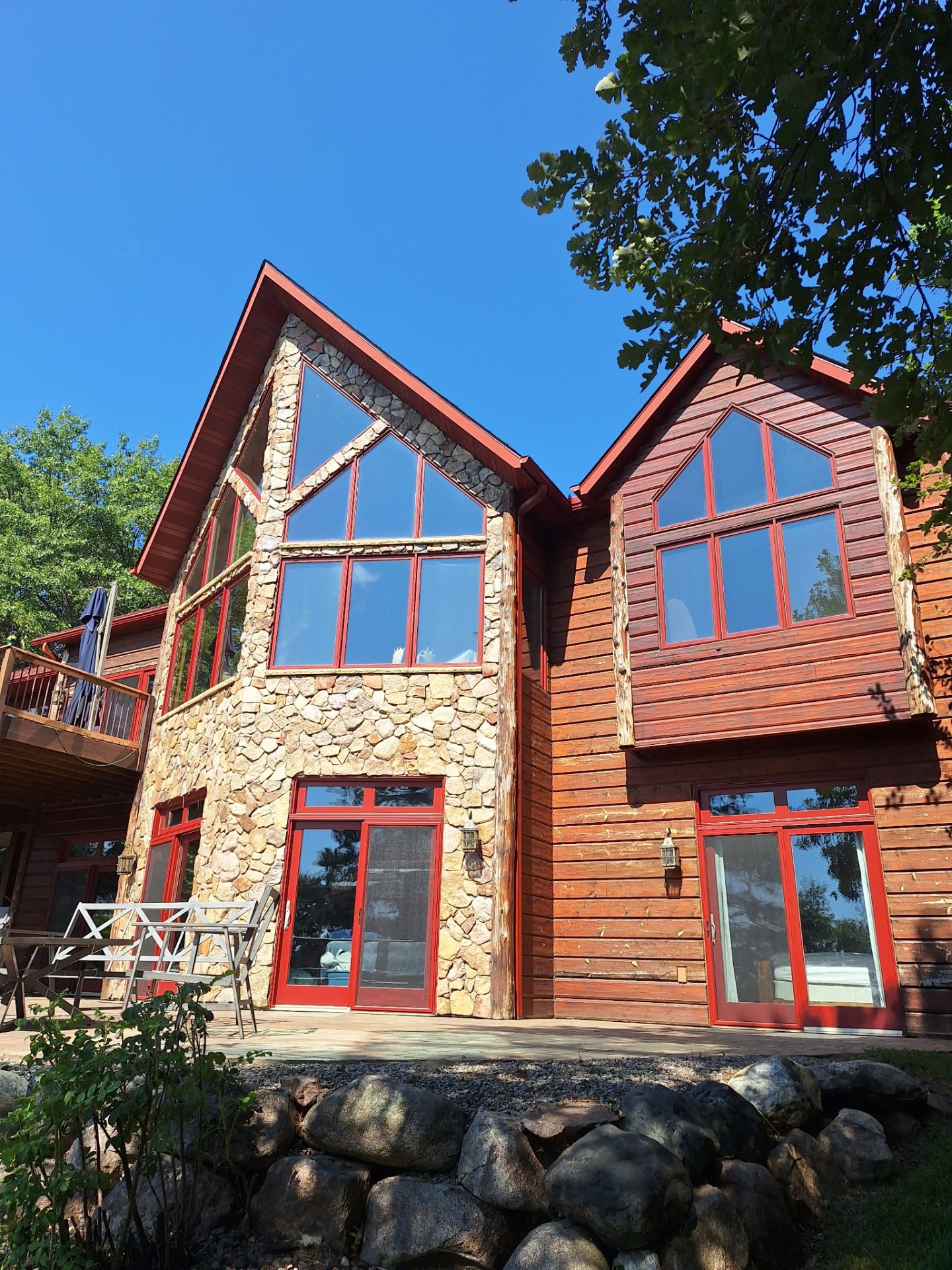 Large log-sided cabin with clean windows and stone accents after full exterior wash